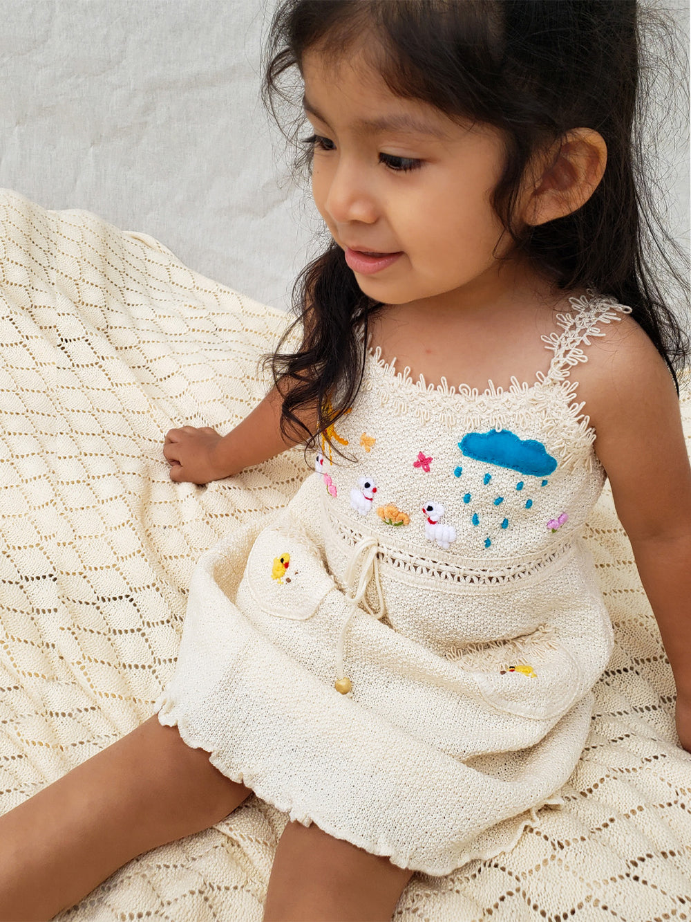 Liten Aventuris Collections. Dress your little star in this Estrella Dress! Featuring a strappy design, two front pockets with intricate cotton knitted lace, and colorful farm animal embroidery, your kiddo will be twinkling bright in no time! With its natural Peruvian Tanguis Cotton and star-inspired name, this dress will make your kids feel like they have the universe in their pocket! Ethically made in Peru. Ekologisk klänning fÜr flickor och bebisar.