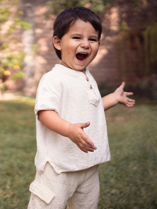 Liten Aventuris Collections. This crafted Luigi Shirt is made of 100% knitted natural Peruvian cotton for a comfortable and lightweight fit. This classic shirt features a mao collar with wooden buttons and a beautifully knitted honeycomb pattern in the opening. It has two apertures on the sides and is finished with knitted trims around the sleeves and base. The loose fit makes it comfortable and perfect for playing. Bomullskläder, barnkläder, Pojken tröja, Skjortor, Natural kläder, ekologisk kläder.
