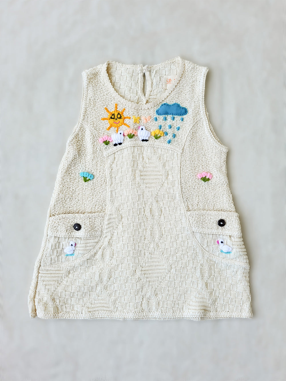 Liten Aventuris Collections. This Nira Dress is made of pure natural Peruvian tanguis cotton. So it's as comfy as it is stylish! It has a combination of geometric knitted patterns, two diagonal front pockets and decorative coconut buttons. With cute hand embroidery of colorful flowers, and friendly little animals, it's perfect for inspiring any little girl's imagination and bringing happiness to their wardrobe! Ethically made in Peru. Ekologisk klänning fÜr flickor och bebisar.