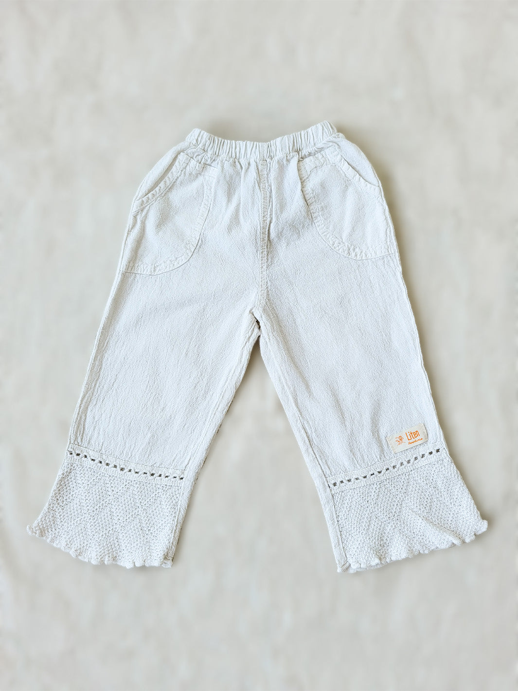 Liten Aventuris brand. Keep your little girl comfy and stylish in our Annie Pants! These natural cotton pants feature playful knitted cotton patterns at the bottom for added breeziness. With front pockets for keeping those special treasures! The soft material will keep your young one feeling silky. Pair this loose-fitting design with our Annie Blouse for the perfect winning combo! Flickan Byxor, Barns bomullskläder, svenska kläder, flickans byxor, ekologisk kläder, babis byxor.