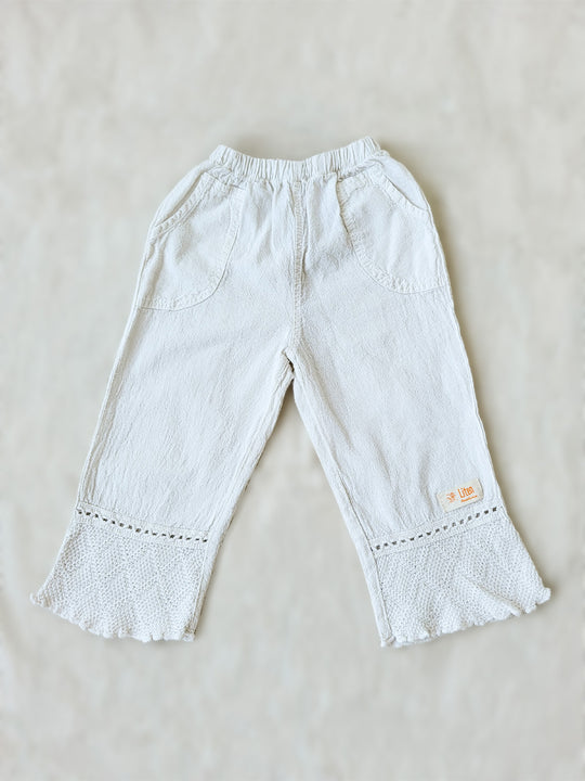 Liten Aventuris brand. Keep your little girl comfy and stylish in our Annie Pants! These natural cotton pants feature playful knitted cotton patterns at the bottom for added breeziness. With front pockets for keeping those special treasures! The soft material will keep your young one feeling silky. Pair this loose-fitting design with our Annie Blouse for the perfect winning combo! Flickan Byxor, Barns bomullskläder, svenska kläder, flickans byxor, ekologisk kläder, babis byxor.