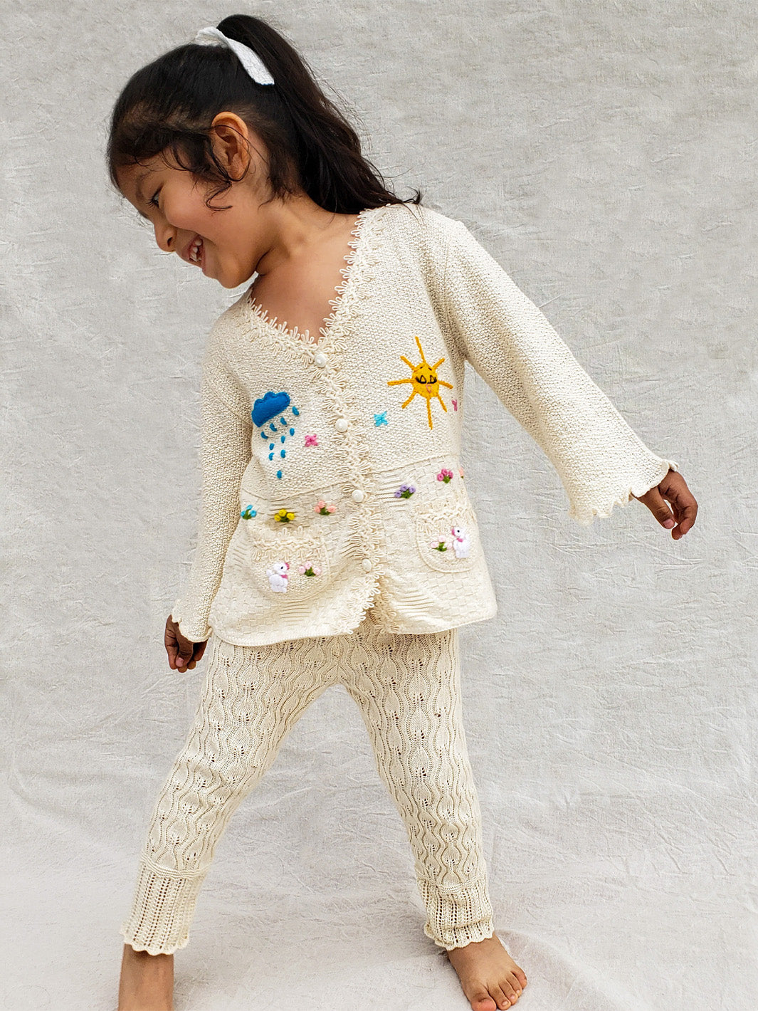 This Sandy Jacket is perfect for your little one's outdoor adventures! Our loose-fit jacket has hand-embroidered farm animals, flowers, and other nature-inspired design elements to give your stylish kid an extra-special look. Plus, two front pockets, and wooden buttons just for fun. Crafted with a combination of regular and geometrical knitted patterns. Liten Aventuris collections. Handbroderade barnkläder, Bomullsjacka, Barnjacka, Babyjacka.