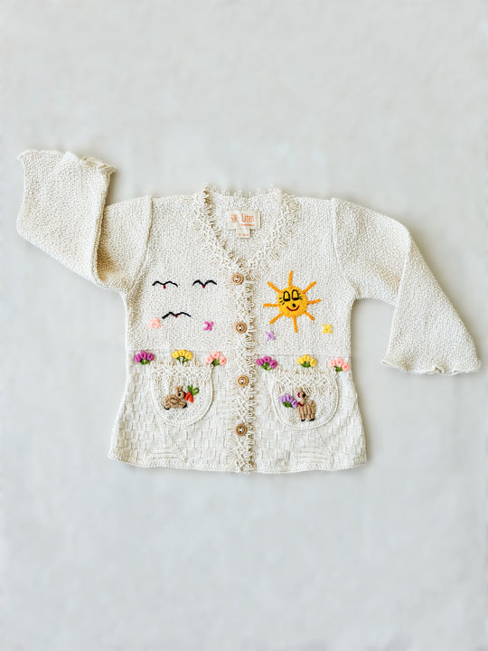 This Sandy Jacket is perfect for your little one's outdoor adventures! Our loose-fit jacket has hand-embroidered farm animals, flowers, and other nature-inspired design elements to give your stylish kid an extra-special look. Plus, two front pockets, and wooden buttons just for fun. Crafted with a combination of regular and geometrical knitted patterns. Liten Aventuris collections. Handbroderade barnkläder, Bomullsjacka, Barnjacka, Babyjacka.