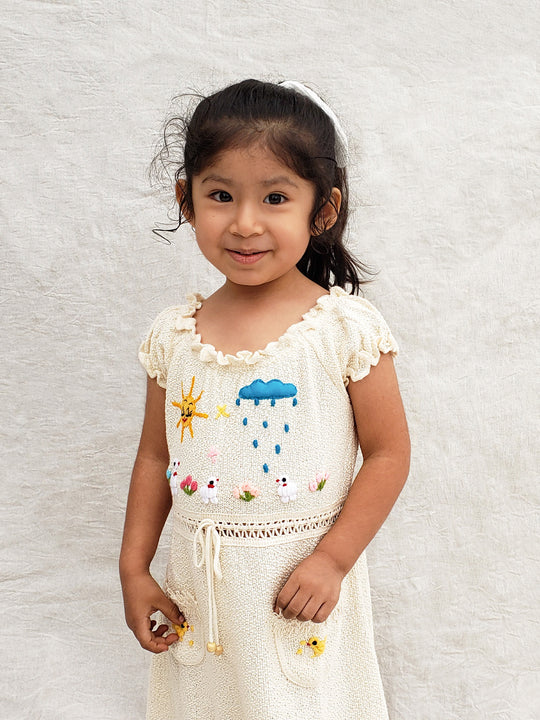 Liten Aventuris Collections. Let your little one shine like the sun in our Sol Dress! Perfect for summer days with its puffed sleeves, wavy edges, two pockets, and colorful hand-embroidered elements inspired by nature, farm animals, and – of course – the happy sun! The Sol dress is made of natural knitted Tanguis cotton. This dress is a comfy, stylish pick for your little explorer! Ethically made in Peru. Ekologisk klänning för flickor och bebisar.