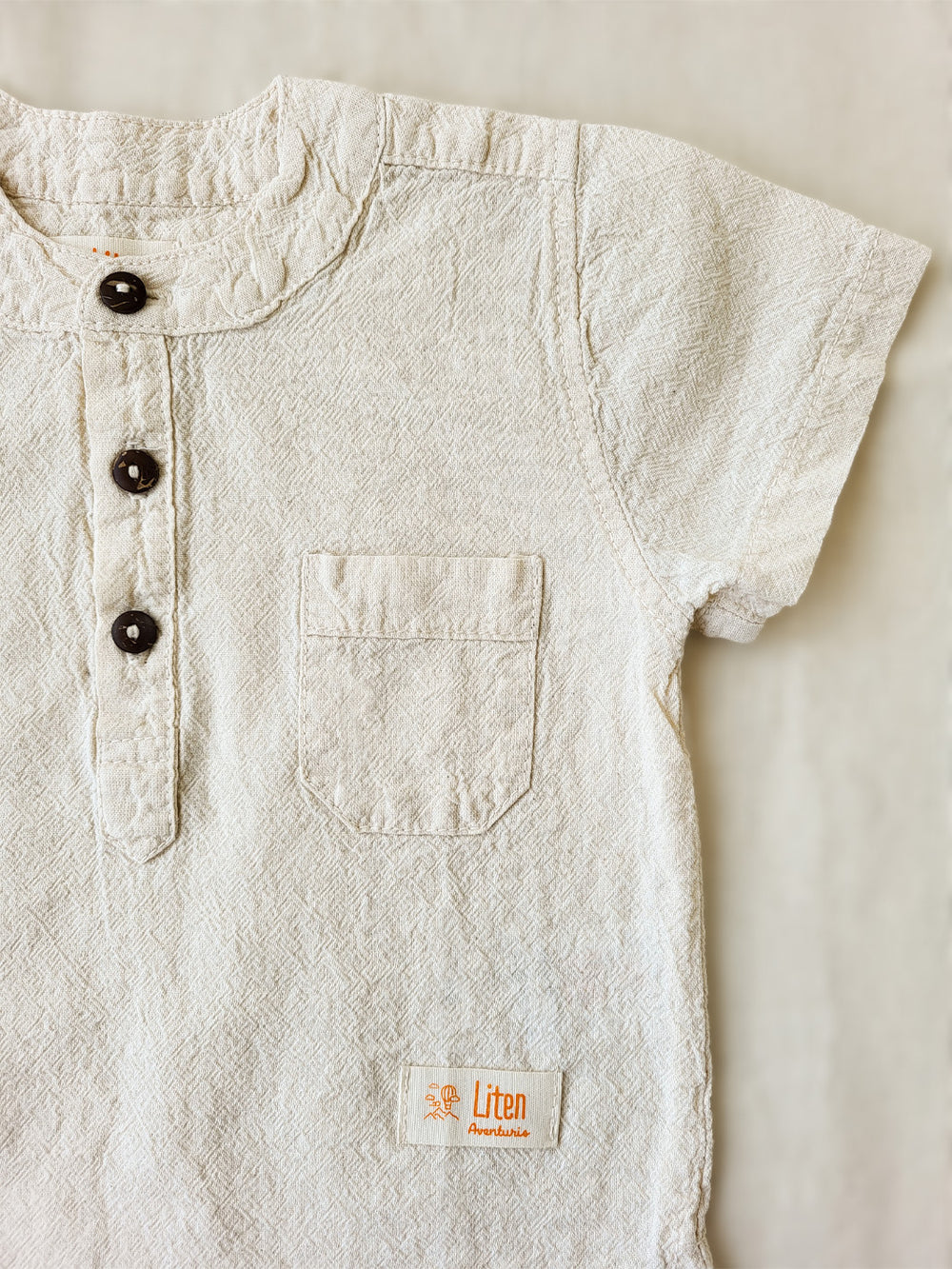 Liten Aventuris Natural Tocuyo Cotton shirt for kids. The Philipo shirt is perfect for a picnic at a lake or a nice morning stroll! This short sleeve shirt with coconut buttons and tunisian collar is casual and chic at the same time. This loose-fitting shirt with one pocket, is comfortable and soft with the skin. Ethically made in Peru. Bomullskläder, barnkläder, Pojken tröja, Natural kläder, ekologisk kläder.