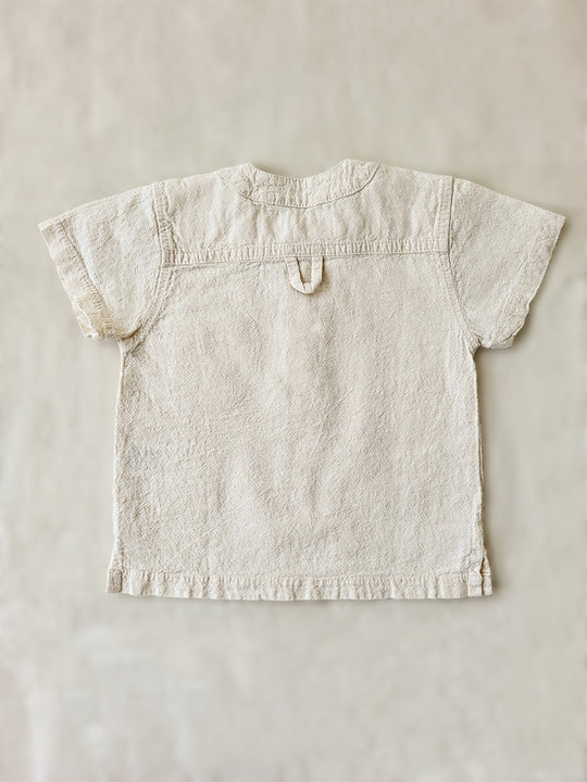 Liten Aventuris Natural Tocuyo Cotton shirt for kids. The Philipo shirt is perfect for a picnic at a lake or a nice morning stroll! This short sleeve shirt with coconut buttons and tunisian collar is casual and chic at the same time. This loose-fitting shirt with one pocket, is comfortable and soft with the skin. Ethically made in Peru. Bomullskläder, barnkläder, Pojken tröja, Natural kläder, ekologisk kläder.