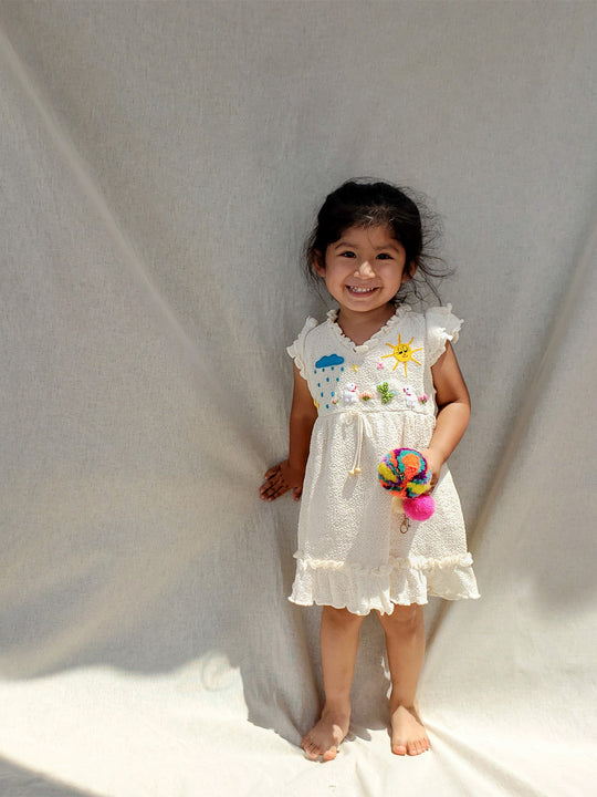 Liten Aventuris Collections. A dream fit for your little girl! Our Tanya Dress has an A-line fit and fun double-layer butterfly sleeves perfect for twirling and dancing. Made of knitted cotton fabric with hand embroidery inspired by nature. Embroidered by Peruvian artisans, this dress brings a touch of whimsy with its decorative fringe. Let your little one explore the world in style! Bomullsklänning för babis och flickor.