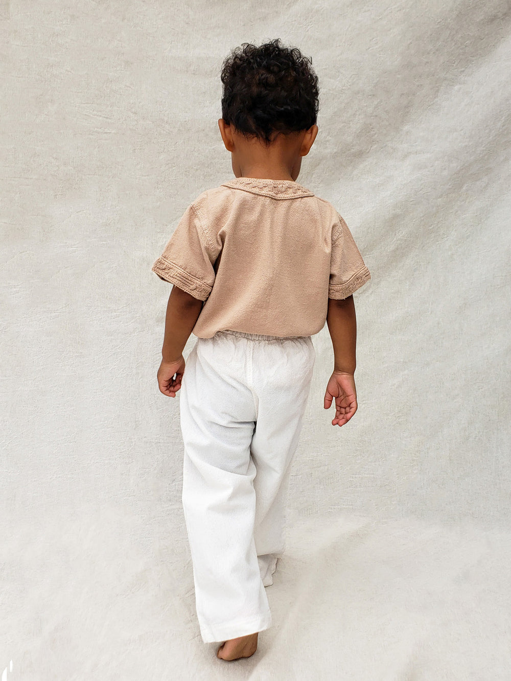 The wide-fit short sleeve Marco shirt is great for adventures! With its Tunisian collar covered in coconut buttons and decorative knitted cotton pattern, this shirt is perfect for chic and casual summer days. This bonny shirt has a front pocket where kids can save their most valuable treasures. Liten Aventuris. Ethically made in Peru. Bomullskläder, barnkläder, Pojken trÜja, Skjortor, Natural kläder, ekologisk kläder.