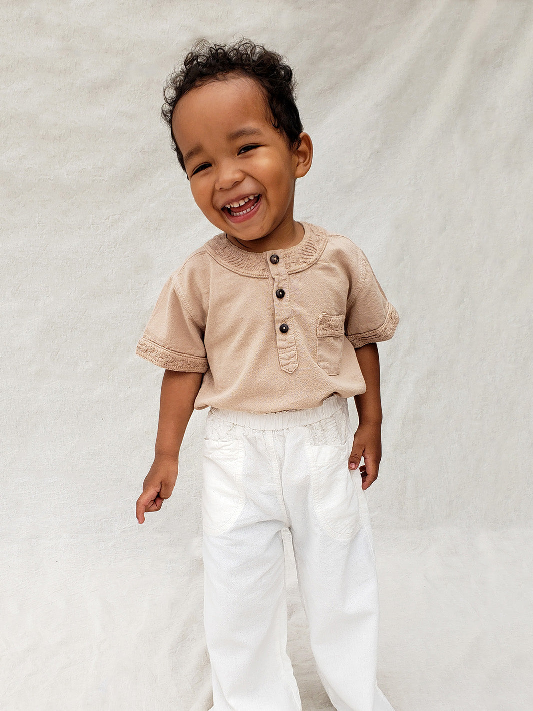 The wide-fit short sleeve Marco shirt is great for adventures! With its Tunisian collar covered in coconut buttons and decorative knitted cotton pattern, this shirt is perfect for chic and casual summer days. This bonny shirt has a front pocket where kids can save their most valuable treasures. Liten Aventuris. Ethically made in Peru. Bomullskläder, barnkläder, Pojken trÜja, Skjortor, Natural kläder, ekologisk kläder.