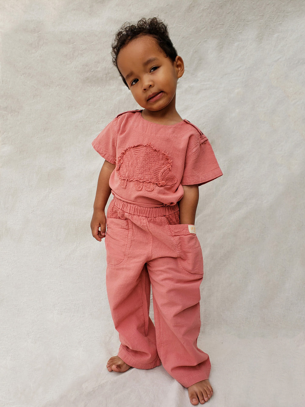 The Olve pants are light and very comfortable. Excellent for traveling or playing outside!  These loose-fit pants provide freedom of movement. And the lateral pockets at the front are internally layered with a knitted-cotton pattern. This gives the perfect artisanal touch.  Mix and match different outfits with any top from any of our Liten Aventuris collections. Unisex cotton pants. Barnkläder, Bomullskläder, Natural kläder. Flicka, pojken och babis kläder. Barn Byxor.