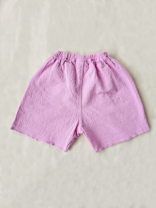 Take her on an adventure in style with these Liss Shorts! Made from natural cotton in a vibrant Malva pink color, they're the perfect combo of cute and comfy. And of course, those front pockets with knitted cotton ruffles - because no outfit is complete without a little something extra! Pair the Liss Shorts with any top from our Liten Aventuris collections and your little one will be ready to take on any challenge! Flickan kortbyxor, barn bomullskläder.