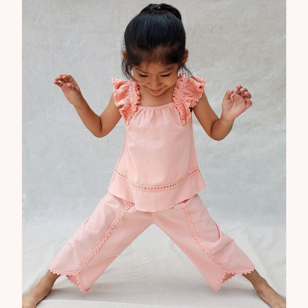 Girl posing in pink Milka Blouse and Lorin Pants made of cotton | Flicka poserar i rosa Milka-blus och Lorin-byxor bomull