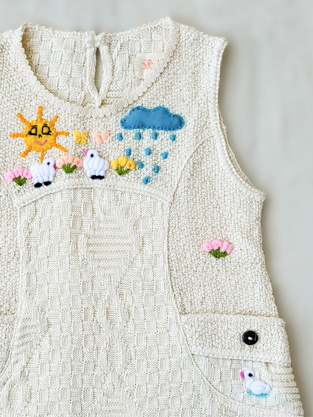 Liten Aventuris Collections. This Nira Dress is made of pure natural Peruvian tanguis cotton. So it's as comfy as it is stylish! It has a combination of geometric knitted patterns, two diagonal front pockets and decorative coconut buttons. With cute hand embroidery of colorful flowers, and friendly little animals, it's perfect for inspiring any little girl's imagination and bringing happiness to their wardrobe! Ethically made in Peru. Ekologisk klänning för flickor och bebisar.
