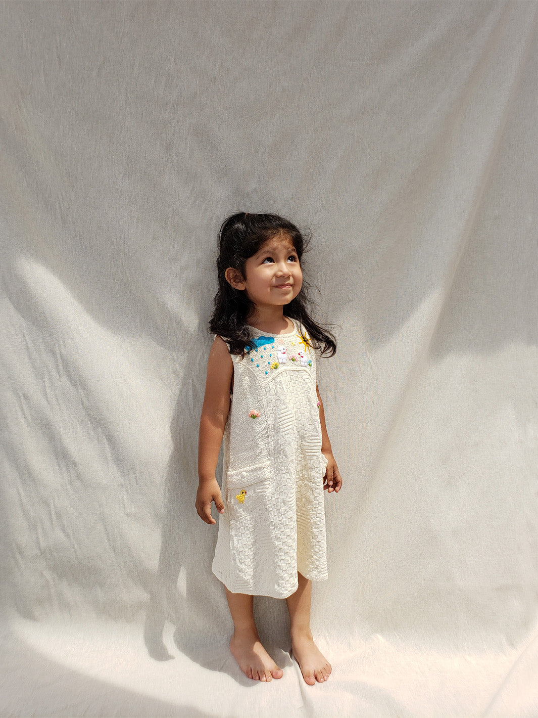 Liten Aventuris Collections. This Nira Dress is made of pure natural Peruvian tanguis cotton. So it's as comfy as it is stylish! It has a combination of geometric knitted patterns, two diagonal front pockets and decorative coconut buttons. With cute hand embroidery of colorful flowers, and friendly little animals, it's perfect for inspiring any little girl's imagination and bringing happiness to their wardrobe! Ethically made in Peru. Ekologisk klänning för flickor och bebisar.