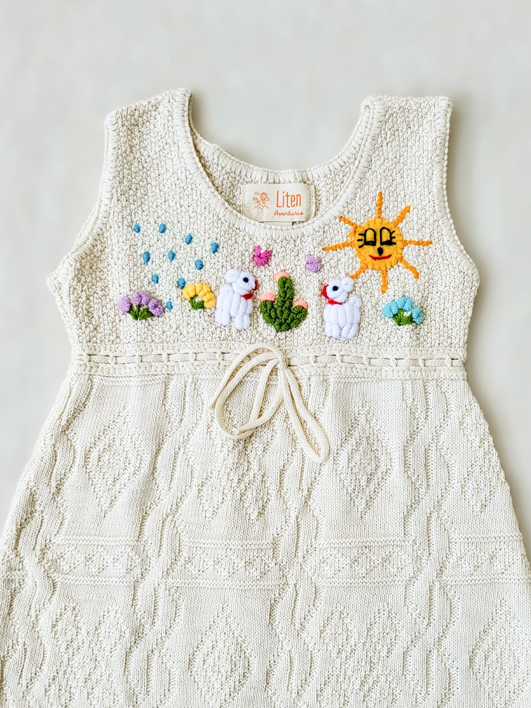 Liten Avevnturis Collections. Our Ñusta dress is the cutest look for your special little one! Delicately hand-embroidered, by Peruvian artisans, with adorable animals and elements from nature. Made in all Peruvian knitted tanguis cotton with delicately knitted terminations. Plus, the bottom part has a fun geometrical design that'll have your mini fashionista stand out from the crowd! Ethically made in Peru. Ekologisk klänning för flickor och bebisar.