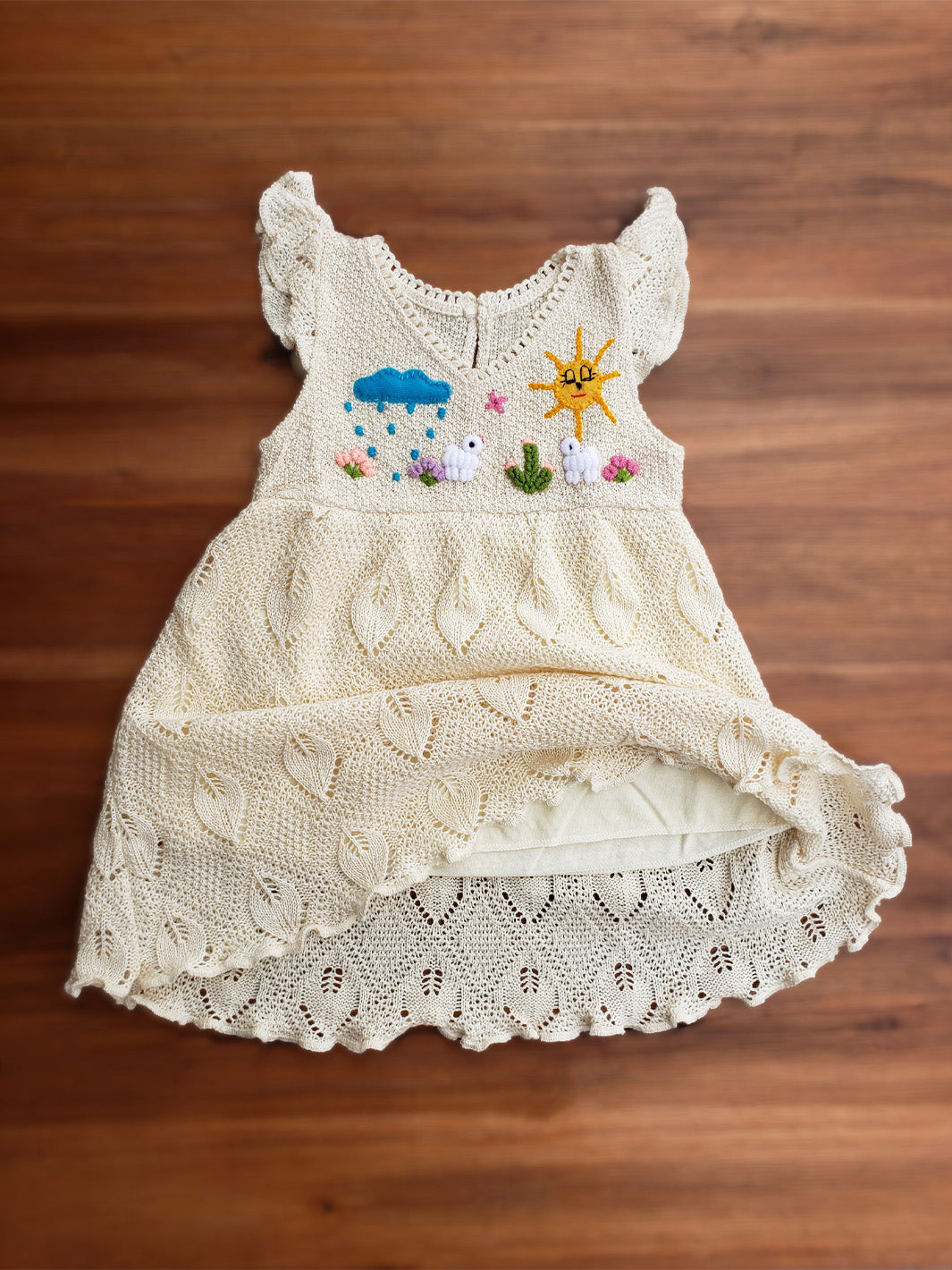 Explore the wild outdoors with your little one in the Pia Dress. Hand-embroidered with colorful designs inspired by farm animals and nature. Its cap sleeves and button behind the neck allow the perfect fit. This unique piece will spark your little one's imagination! A truly artisanal piece, with its natural cotton knitted pattern inspired by leaves and its inner layer in jersey cotton! Ekologisk klänning för flickor och bebisar.