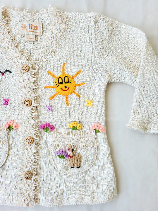 This Sandy Jacket is perfect for your little one's outdoor adventures! Our loose-fit jacket has hand-embroidered farm animals, flowers, and other nature-inspired design elements to give your stylish kid an extra-special look. Plus, two front pockets, and wooden buttons just for fun. Crafted with a combination of regular and geometrical knitted patterns. Liten Aventuris collections. Handbroderade barnkläder, Bomullsjacka, Barnjacka, Babyjacka.